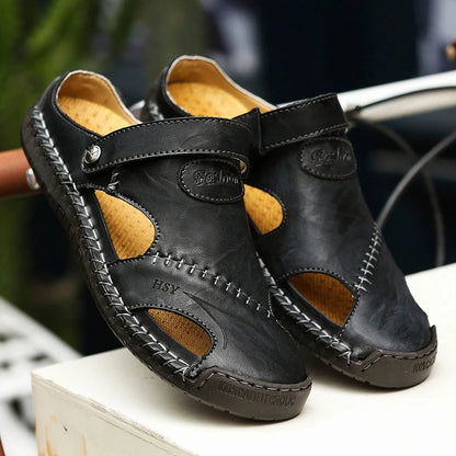 Pair of black leather sandals with brown accents on a white surface.